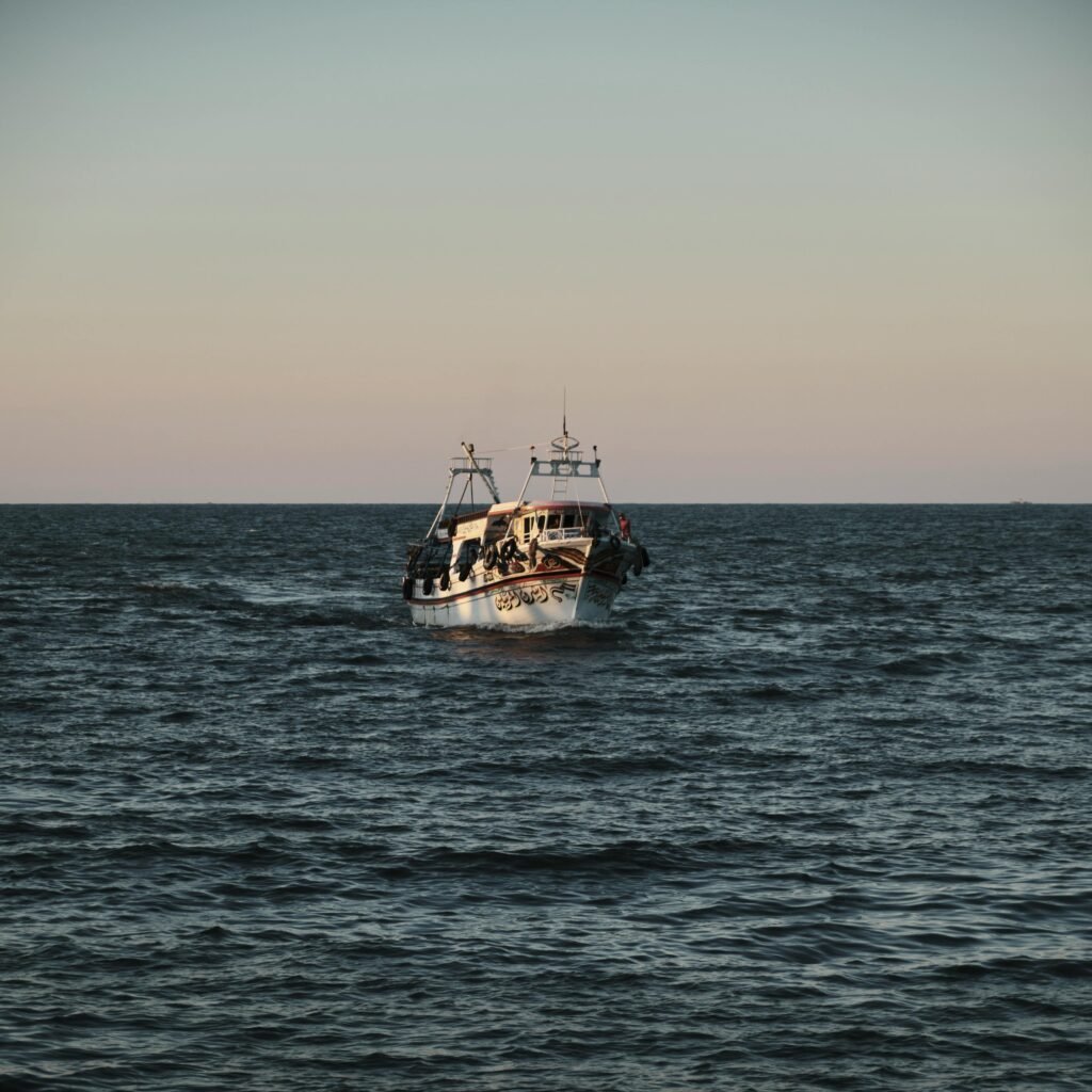 A fishing boat navigates through open waters at twilight, creating a serene nautical scene.